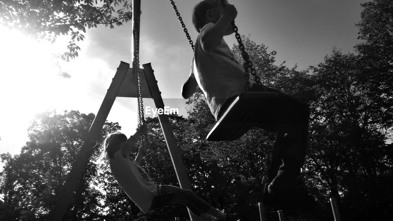 Low angle view of children swinging at park