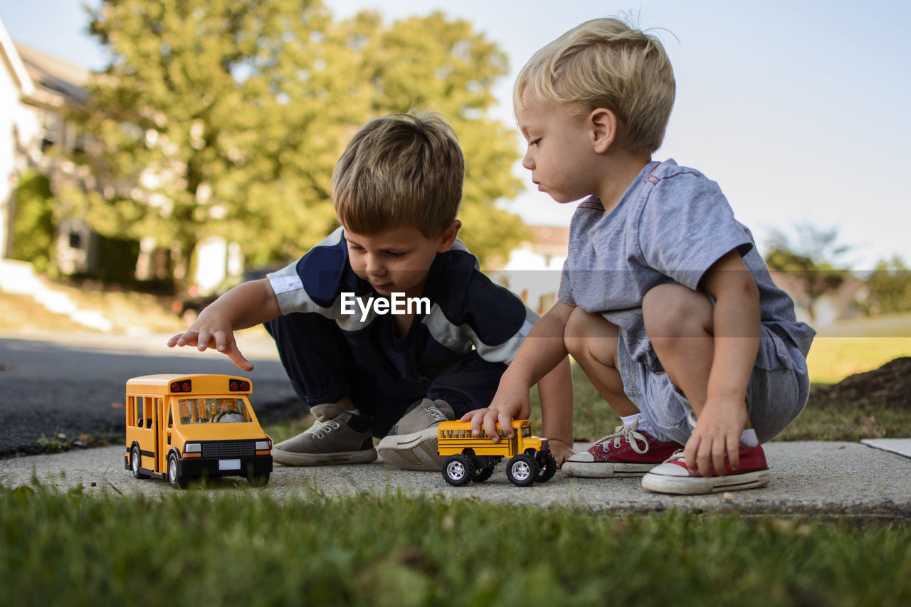 Brothers playing with toys in backyard