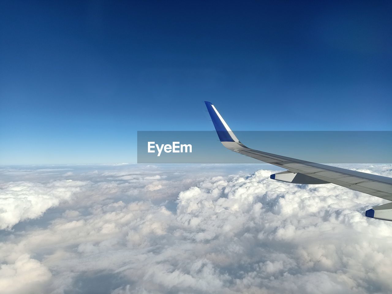 VIEW OF AIRPLANE FLYING OVER CLOUDS