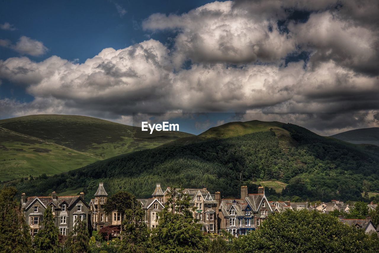 Scenic view of houses by mountains against sky