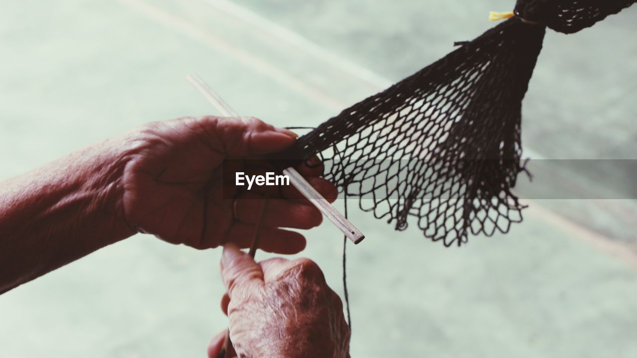 Cropped image of man repairing fishing net