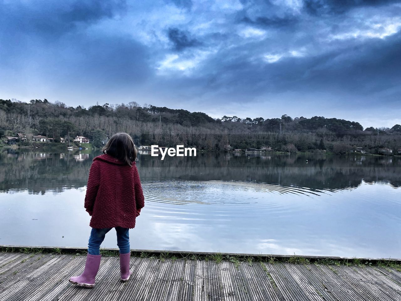 REAR VIEW OF WOMAN STANDING AGAINST LAKE