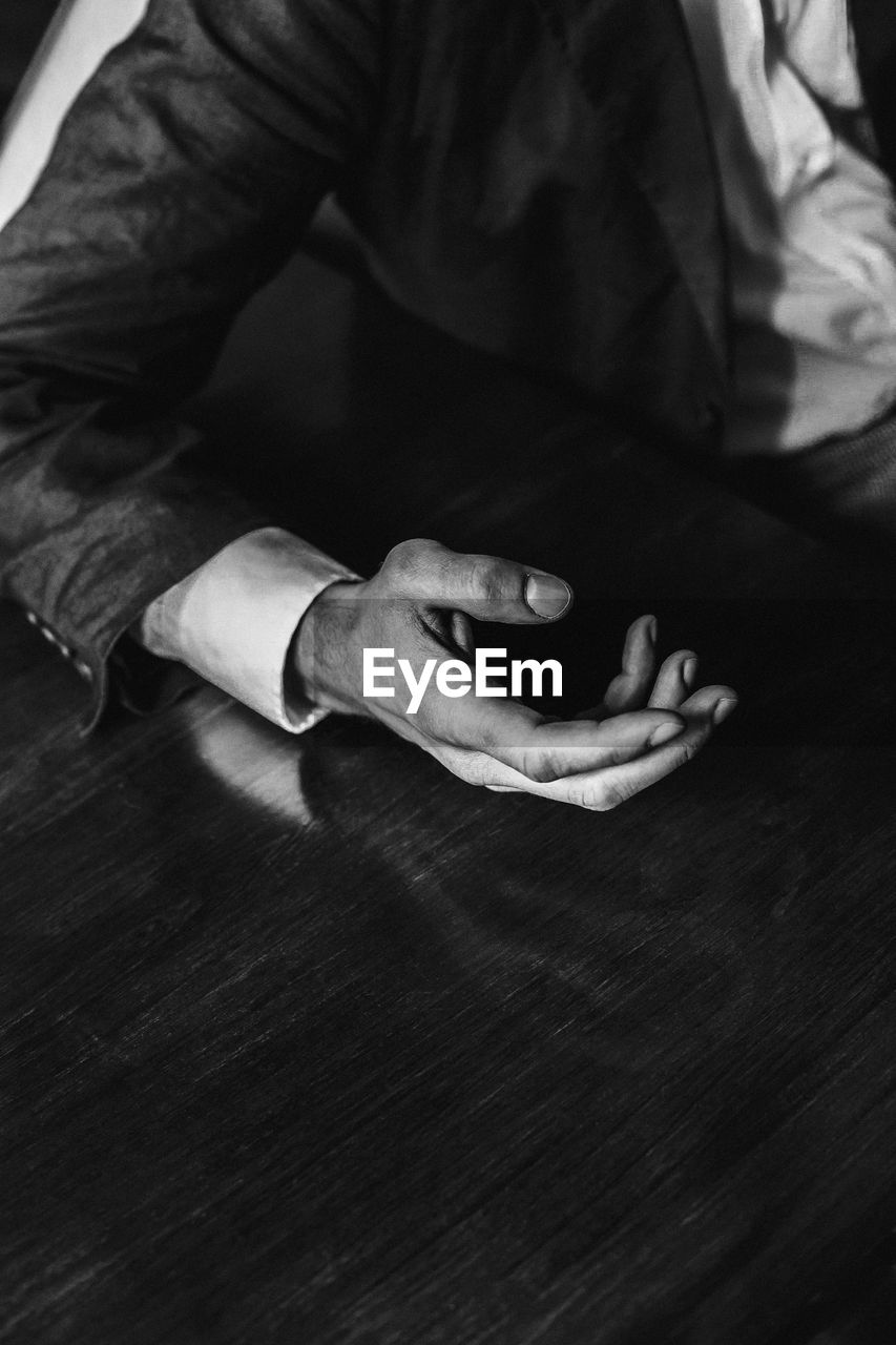 Cropped hand of man gesturing on wooden table