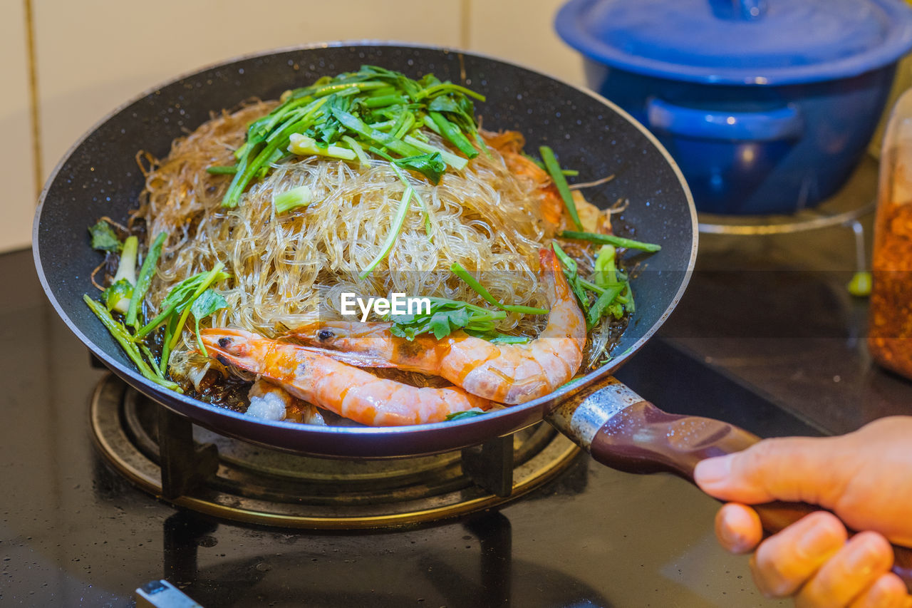 High angle view of person cooking baked shrimp with glass noodles