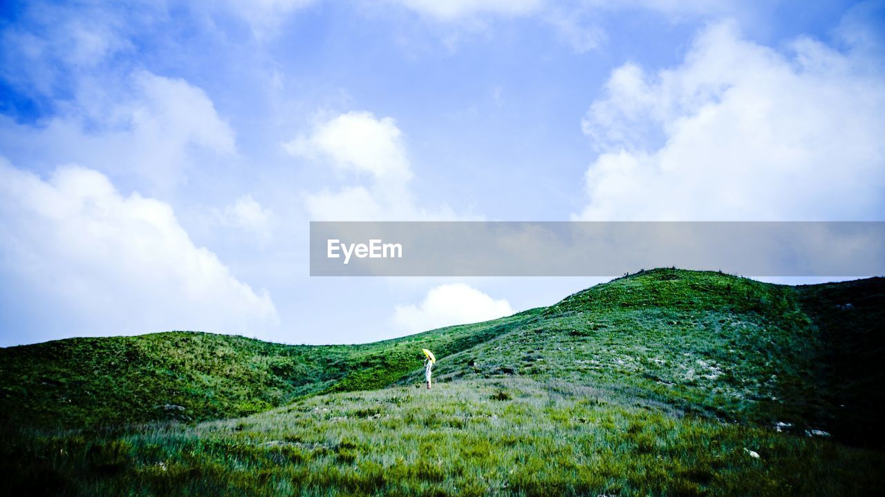 Scenic view of grassy hill against sky