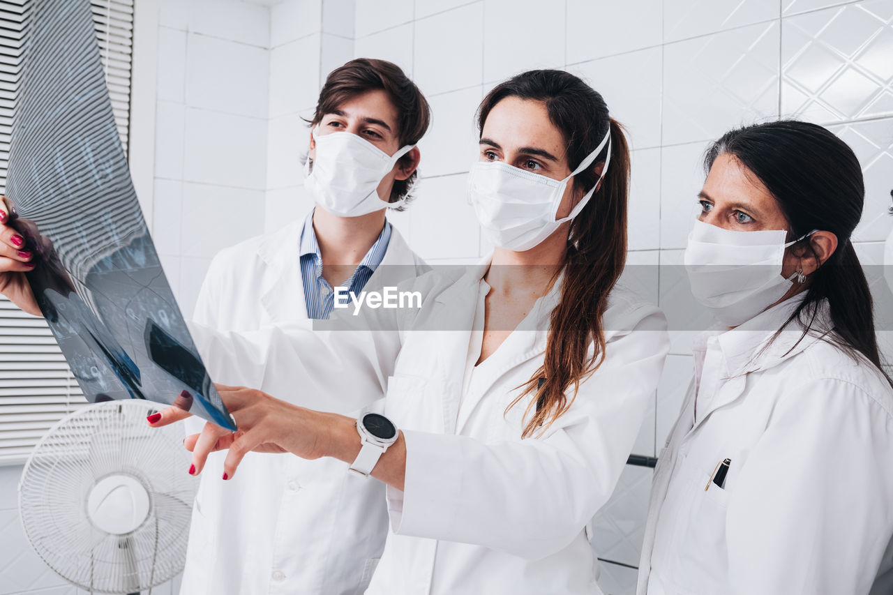 Group of doctors with a mask on their face examining an x-ray in a hospital room