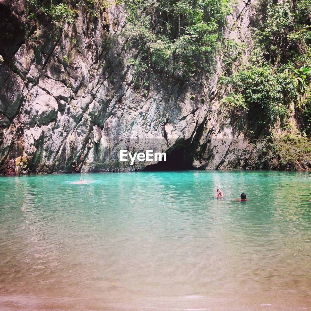 Men swimming in sea against rock formations