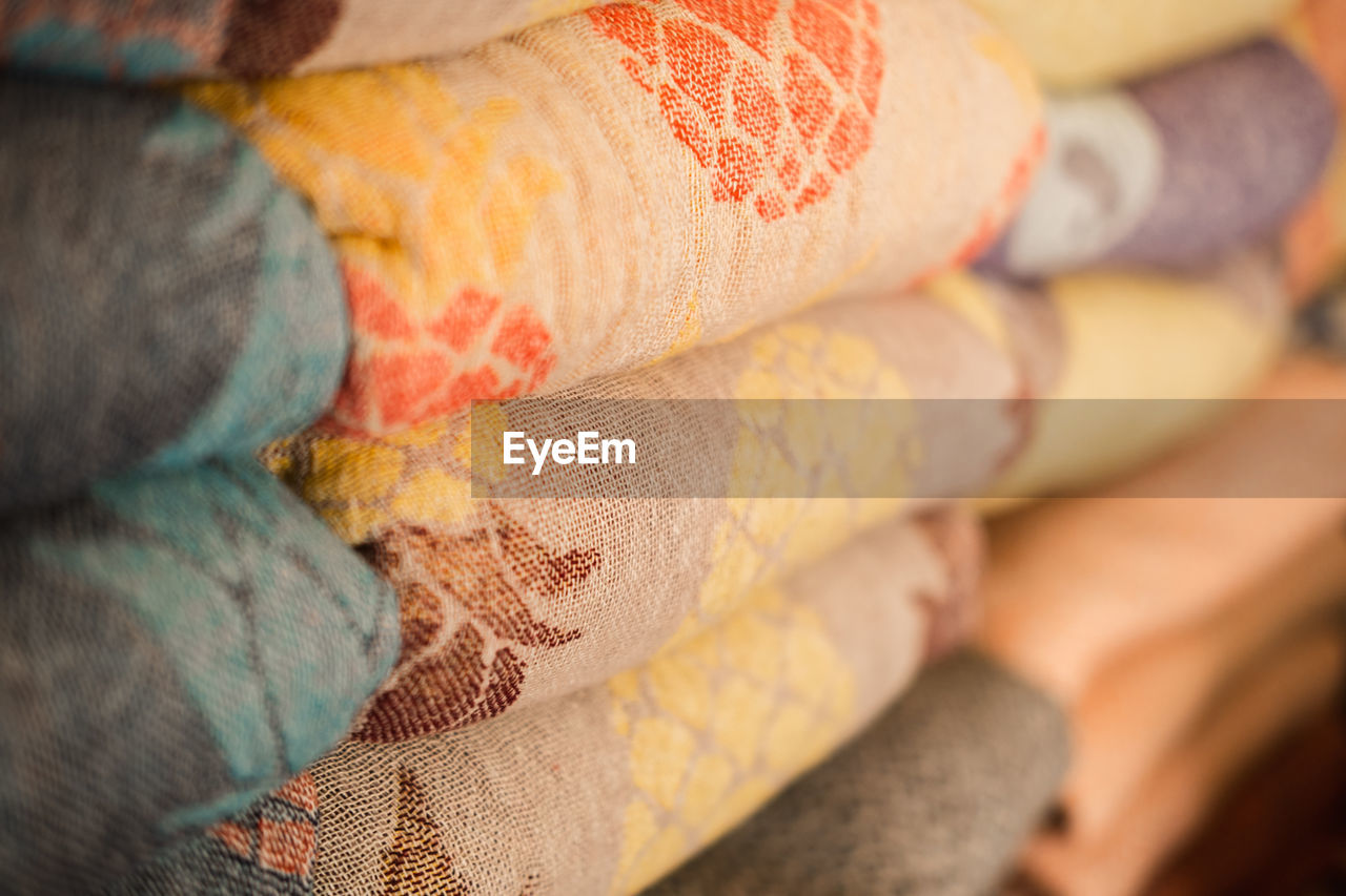 Samples of linen fabrics in a pile on store shelf.