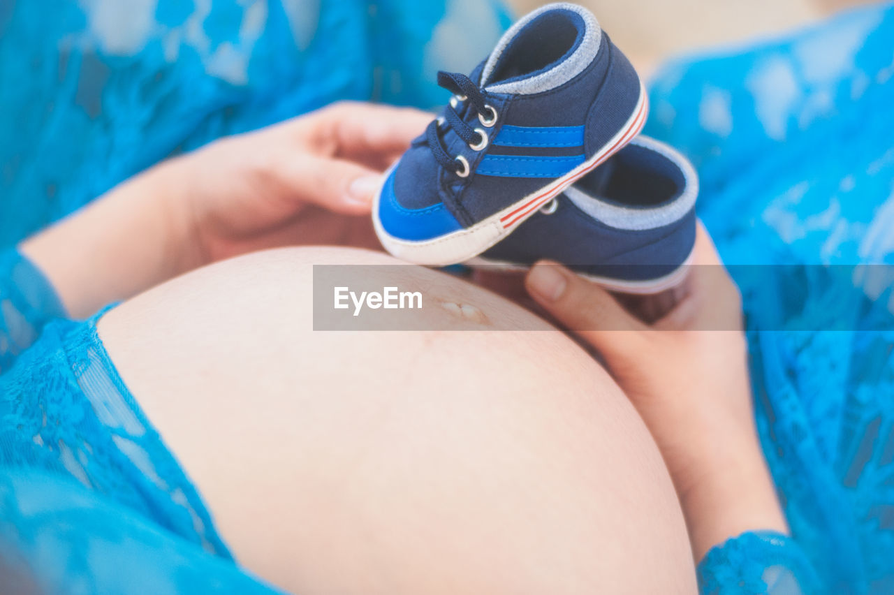 Midsection of pregnant woman holding baby booties