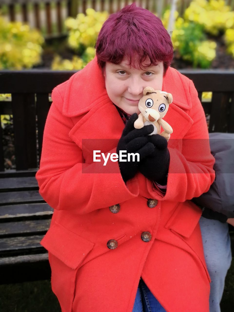 Portrait of mid adult woman holding toy while sitting on bench