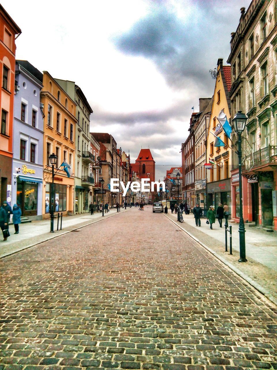 VIEW OF CITY STREET AGAINST CLOUDY SKY