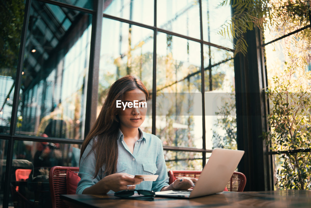 Young woman using laptop at table in cafe