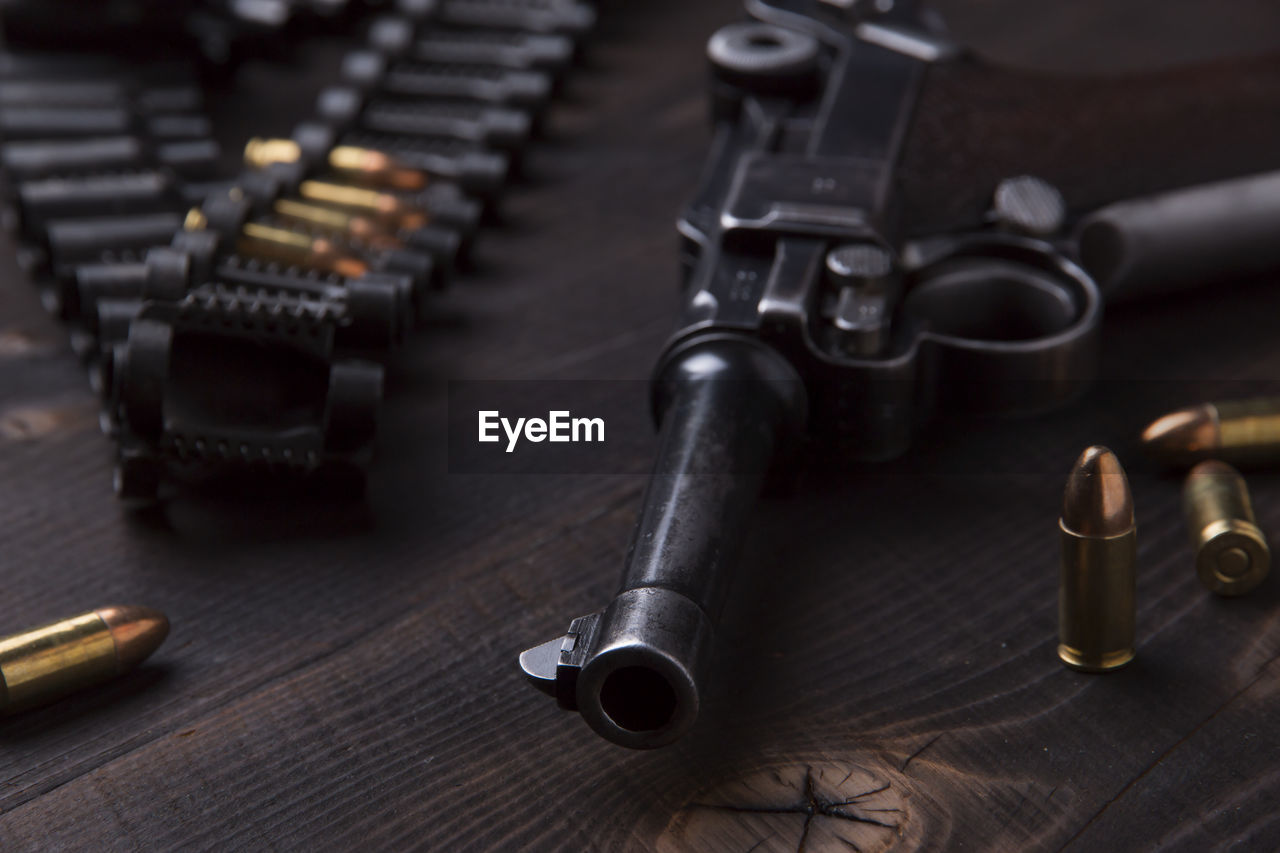 High angle view of handgun and bullets on wooden table