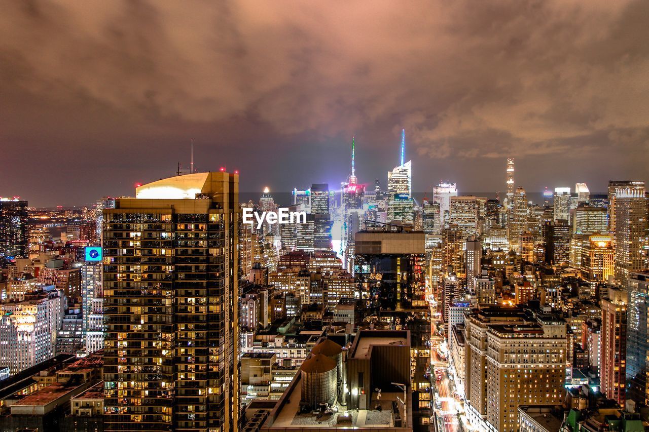 ILLUMINATED MODERN BUILDINGS IN CITY AGAINST SKY