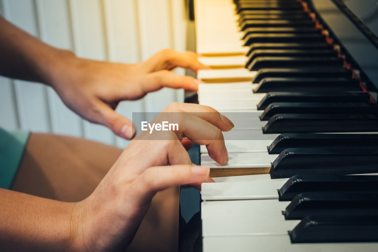 Cropped hands of woman playing piano at home