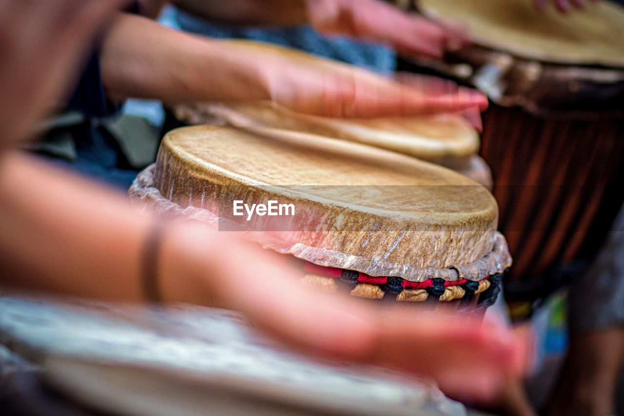 Cropped hands of people playing drums