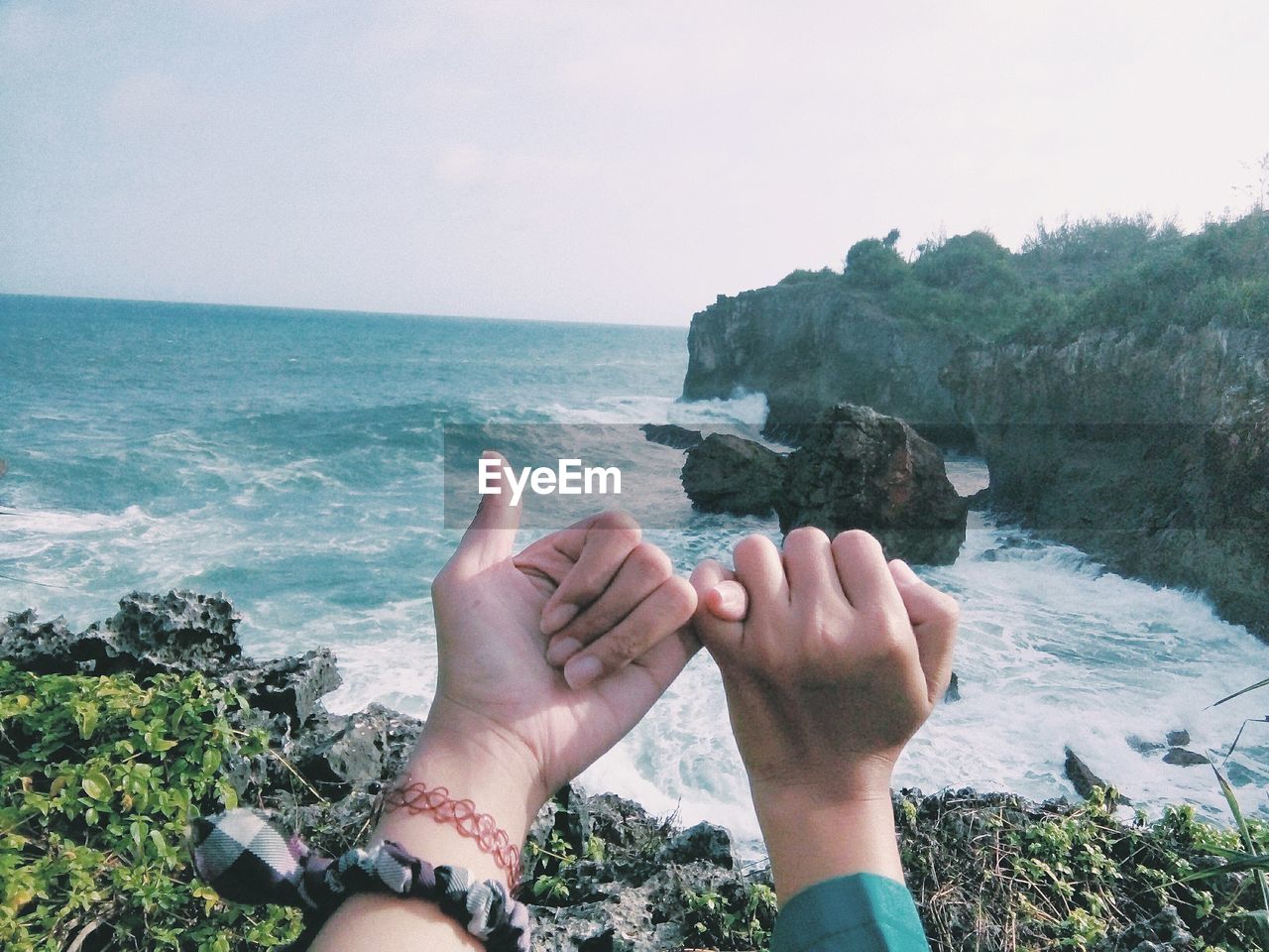 Cropped hands of couple against sea