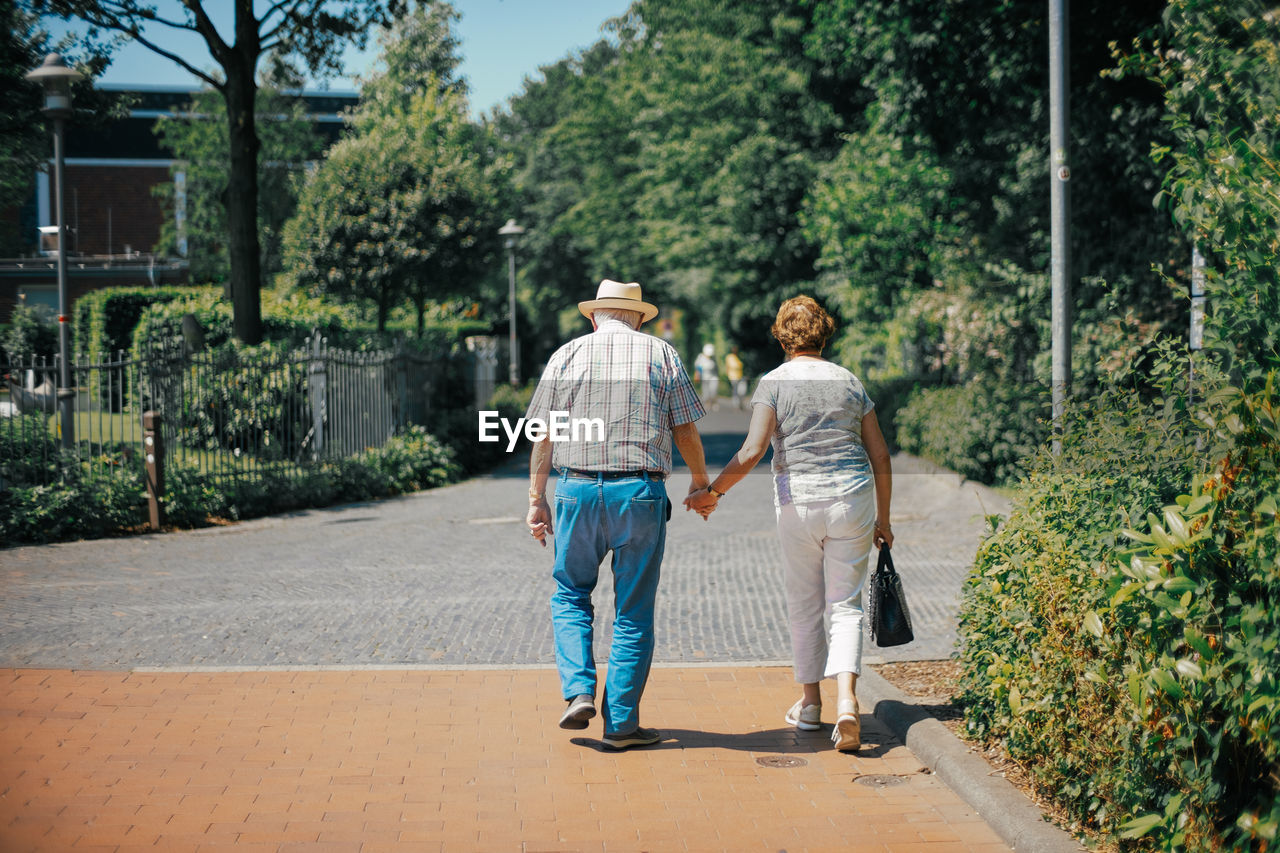 REAR VIEW OF COUPLE WALKING ON ROAD