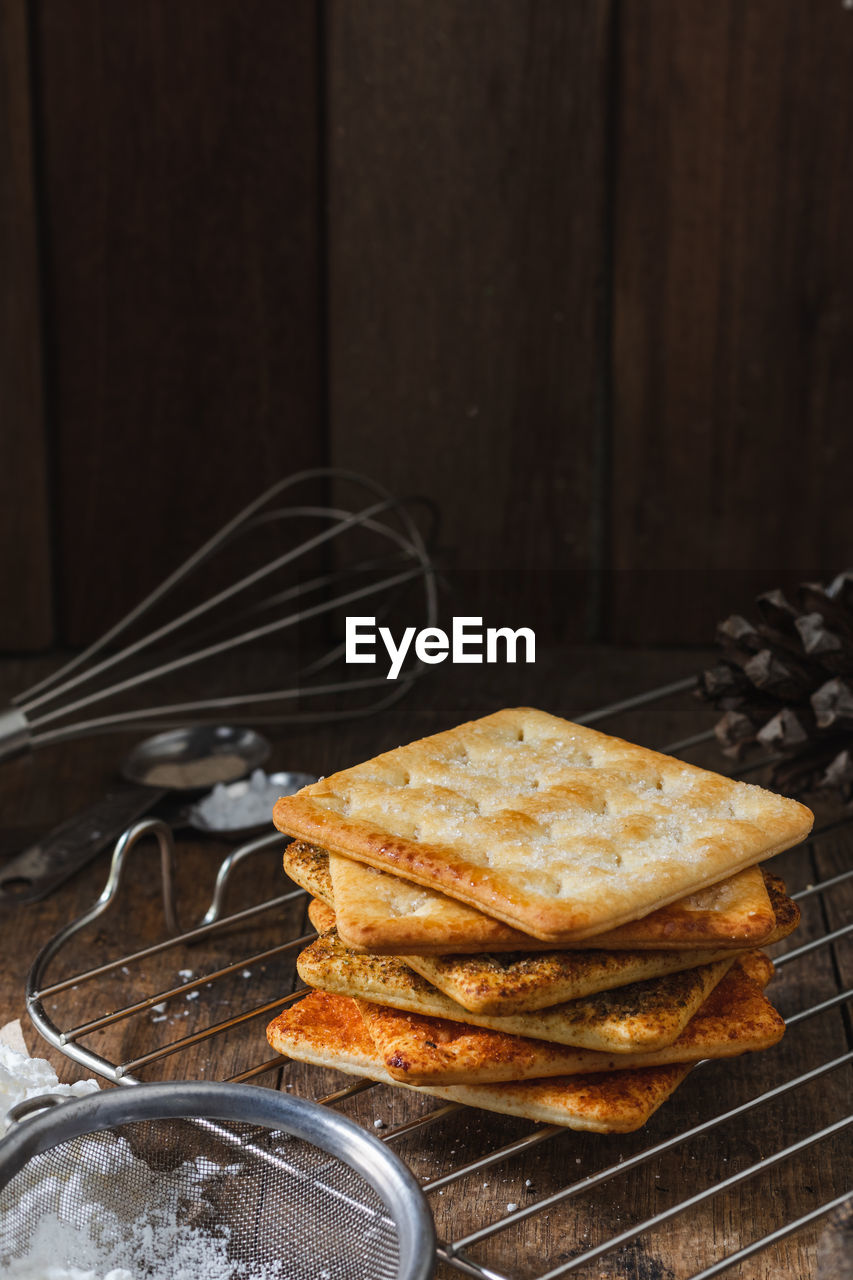 Square dry crackers biscuit on a wooden table. wooden texture dark background. snack dry biscuits