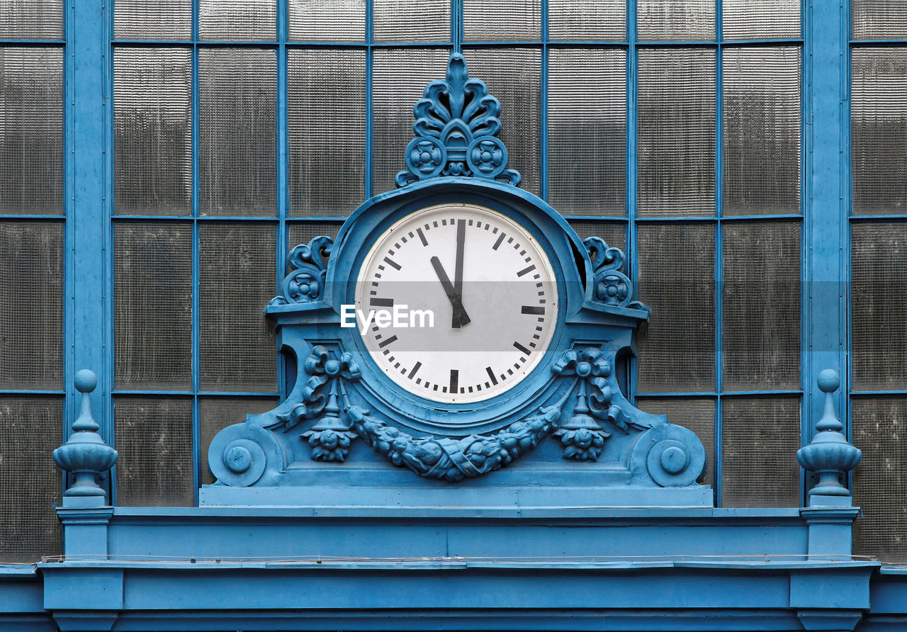 Close-up of blue clock against window