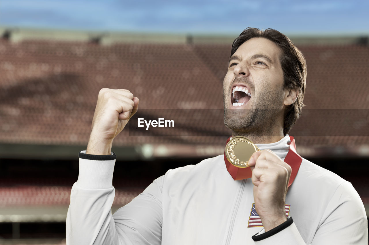 American male athlete smiling after winning a gold medal in a stadium. celebrating his victory.