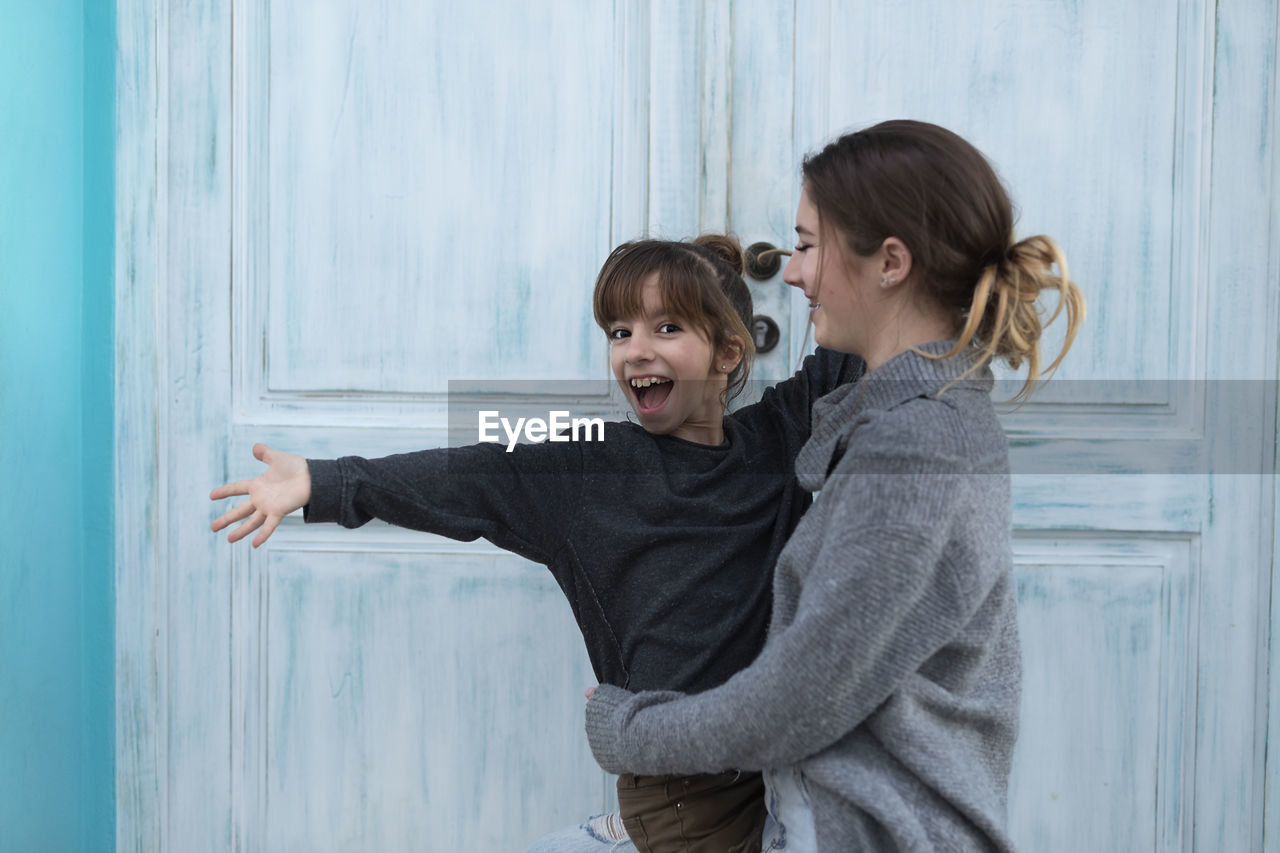 Portrait of daughter with mother standing against door