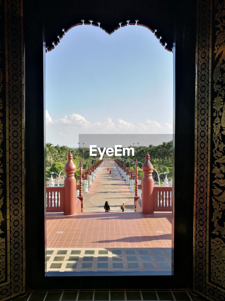Pathway seen through ornate entrance on sunny day