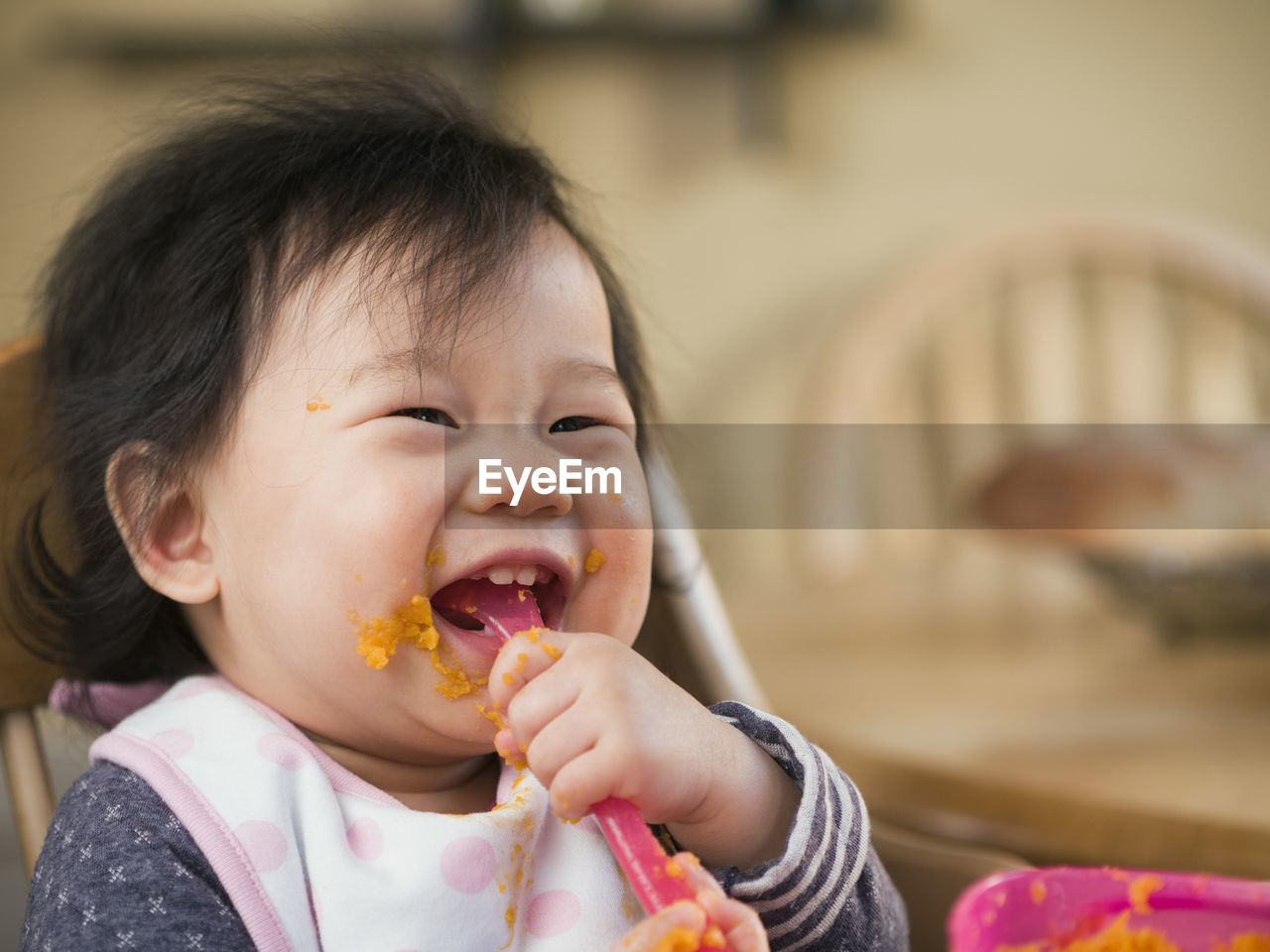 Close-up of cute baby girl eating mashed potatoes at home