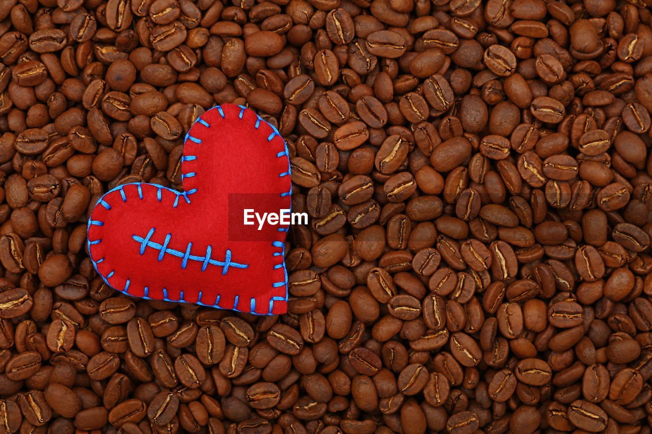 Close-up of heart shape decoration over roasted coffee beans