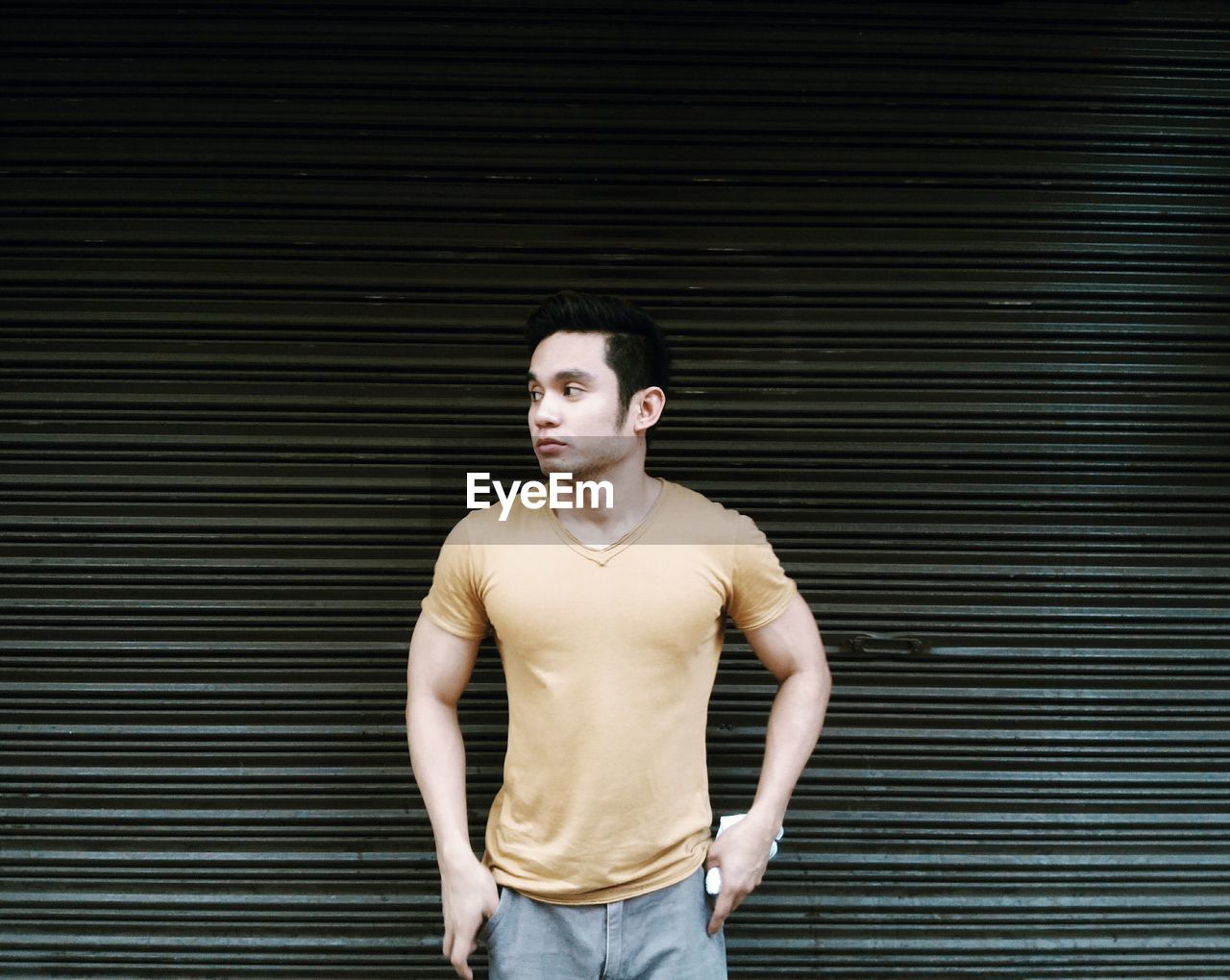 Young man standing against closed shutter