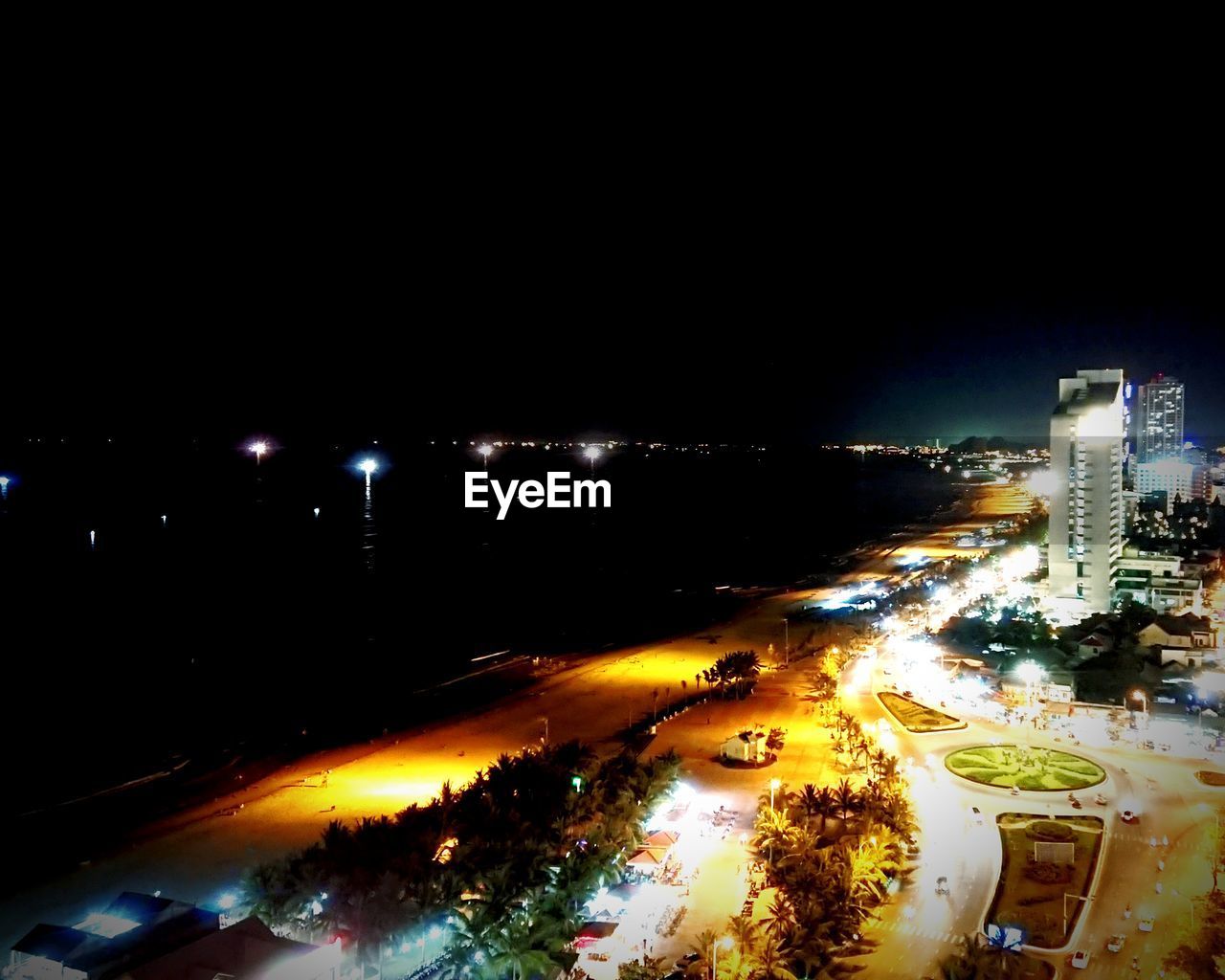 HIGH ANGLE VIEW OF ILLUMINATED STREET AMIDST BUILDINGS AT NIGHT