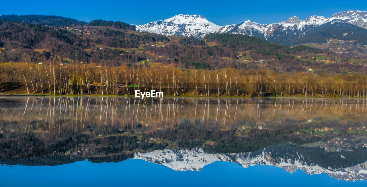 Snow covered mountains reflecting on calm lake