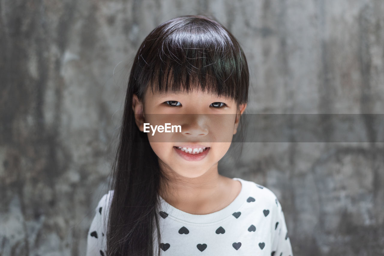 Portrait of smiling girl against wall