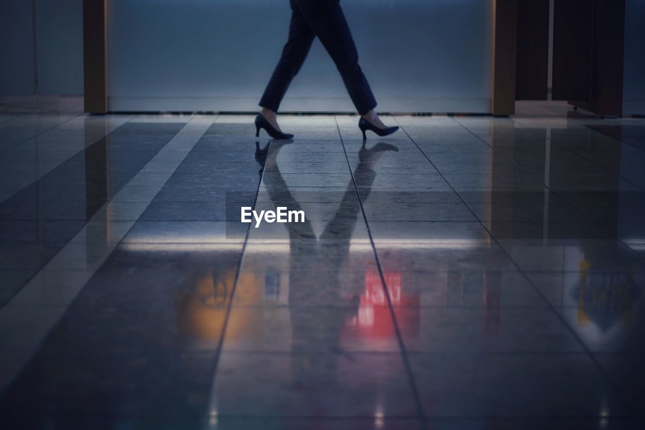 Low section of woman walking on tiled floor