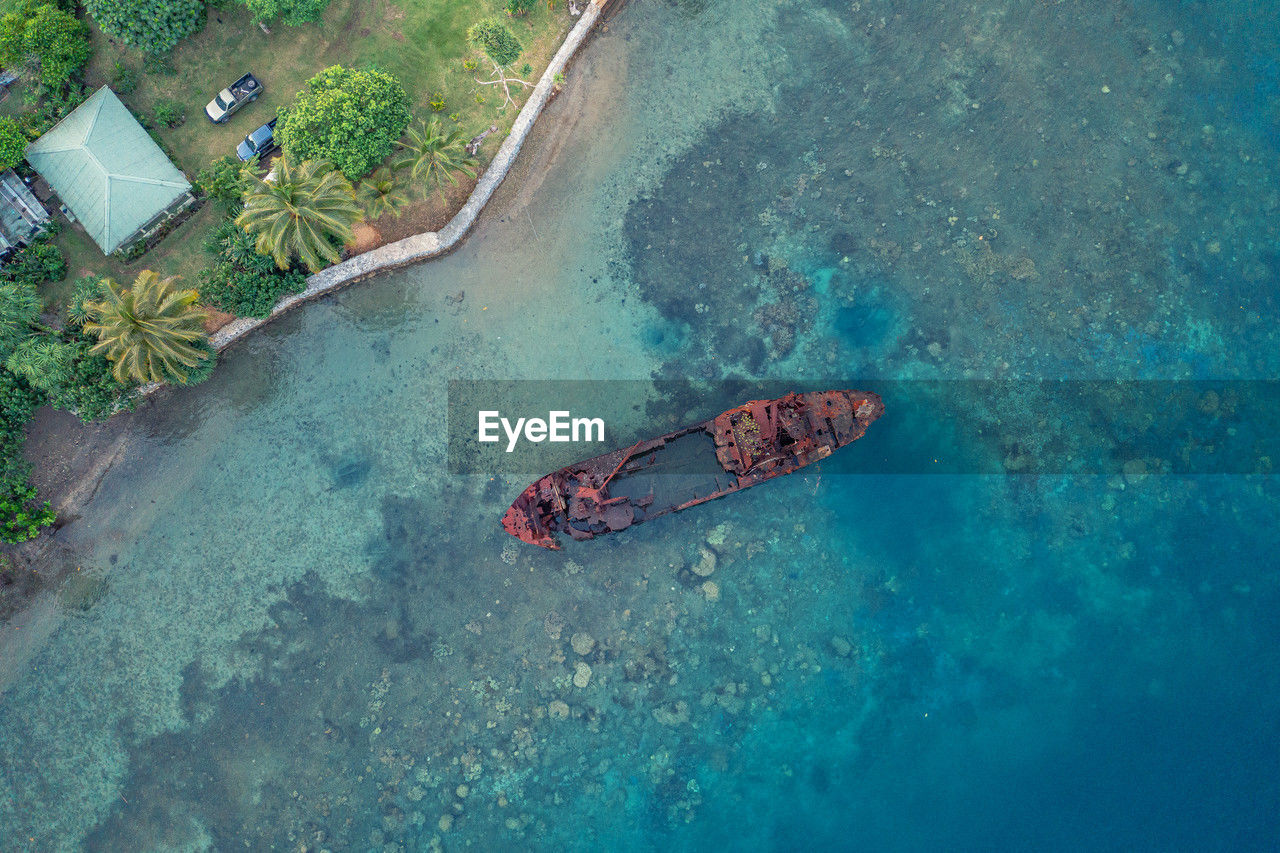 Top view of rusty wrecked boat in turquoise water near tropical shore. drone photo. sanma, vanuatu