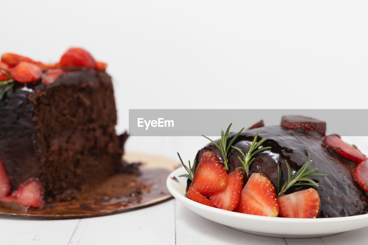 A piece of delicious chocolate cake with strawberries on white background