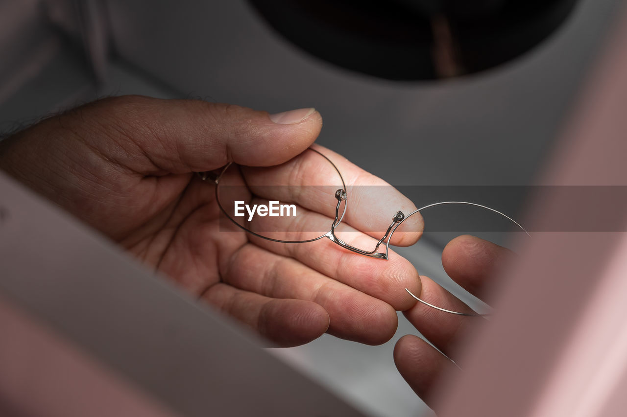 Cropped hand of person holding broken eyeglasses