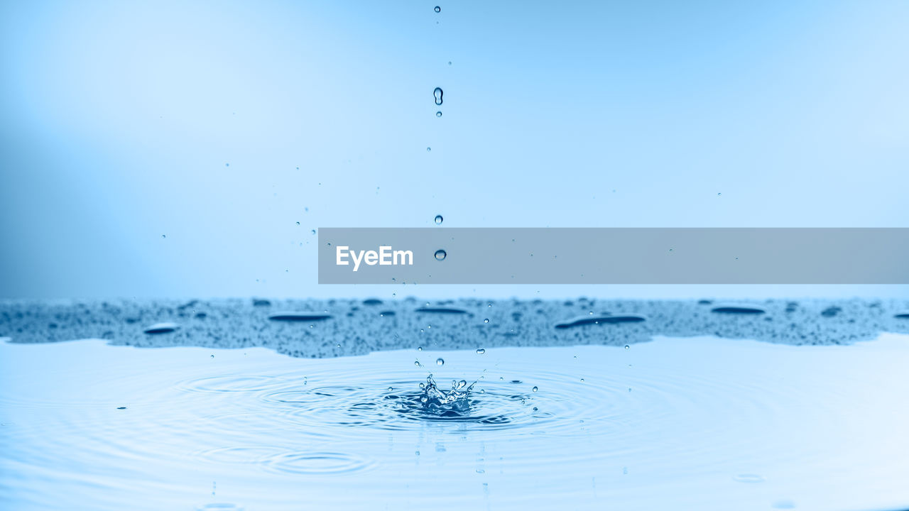 CLOSE-UP OF SPLASHING WATER AGAINST BLUE BACKGROUND