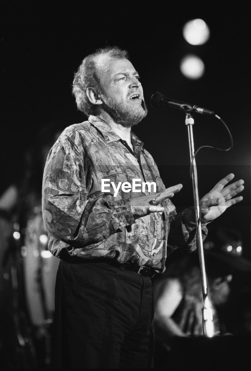 MAN WITH ARMS OUTSTRETCHED STANDING ON STAGE