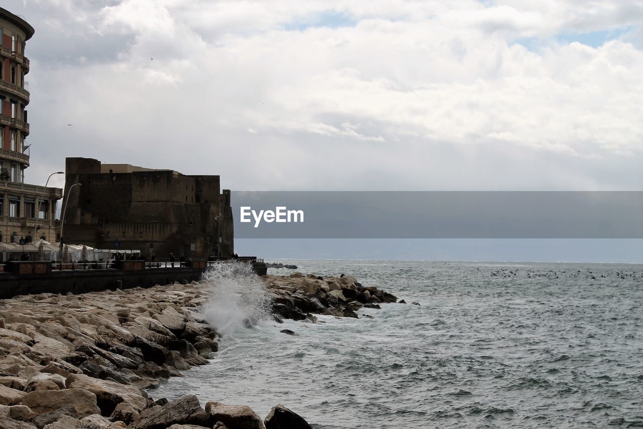water, sea, sky, cloud, coast, ocean, architecture, shore, nature, beach, land, built structure, rock, building exterior, tower, cliff, wave, body of water, building, horizon, scenics - nature, terrain, beauty in nature, travel destinations, horizon over water, no people, history, outdoors, travel, coastline, day, environment, the past, breakwater, bay, motion, tourism