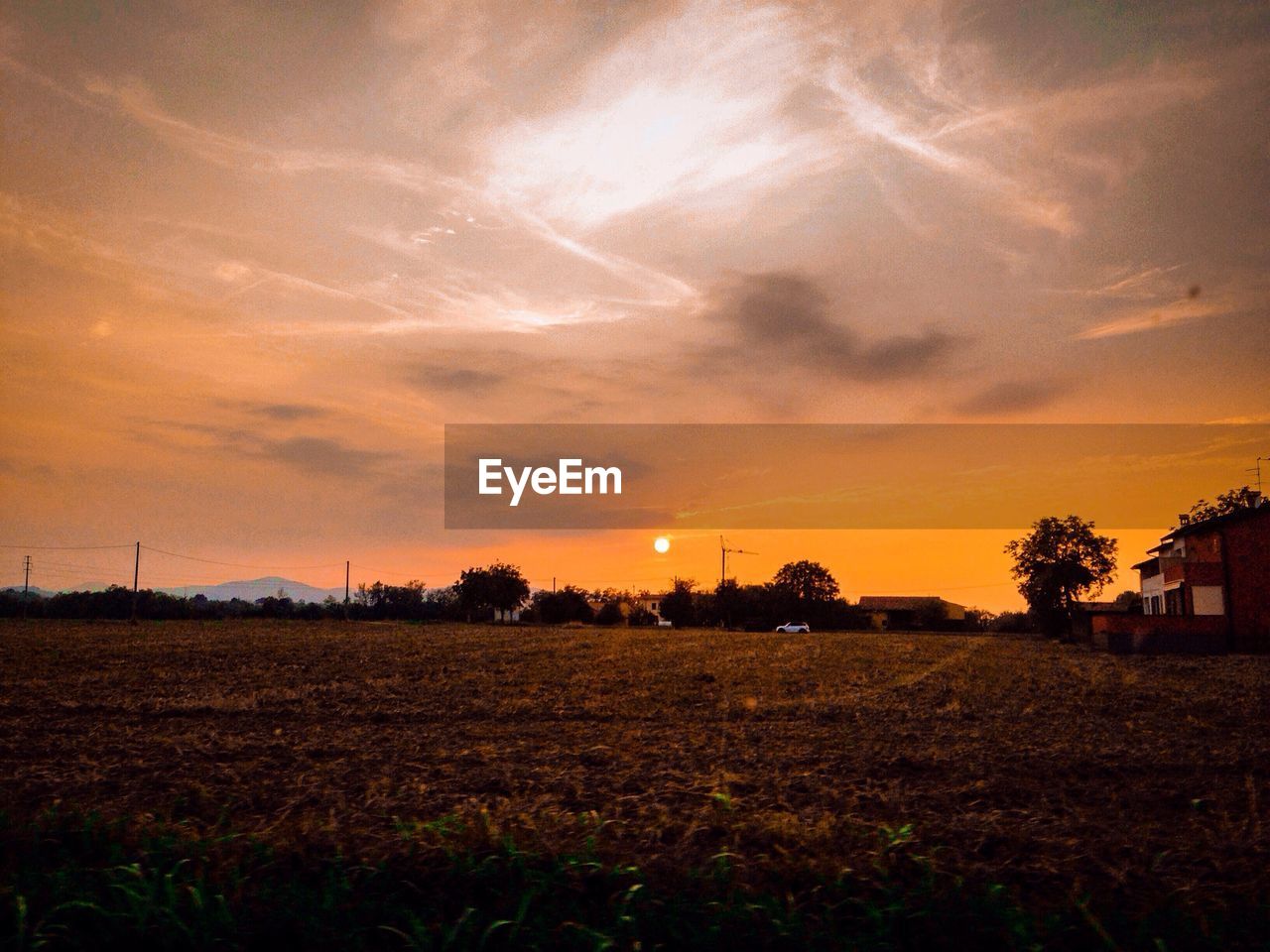 Scenic view of field against cloudy sky at sunset