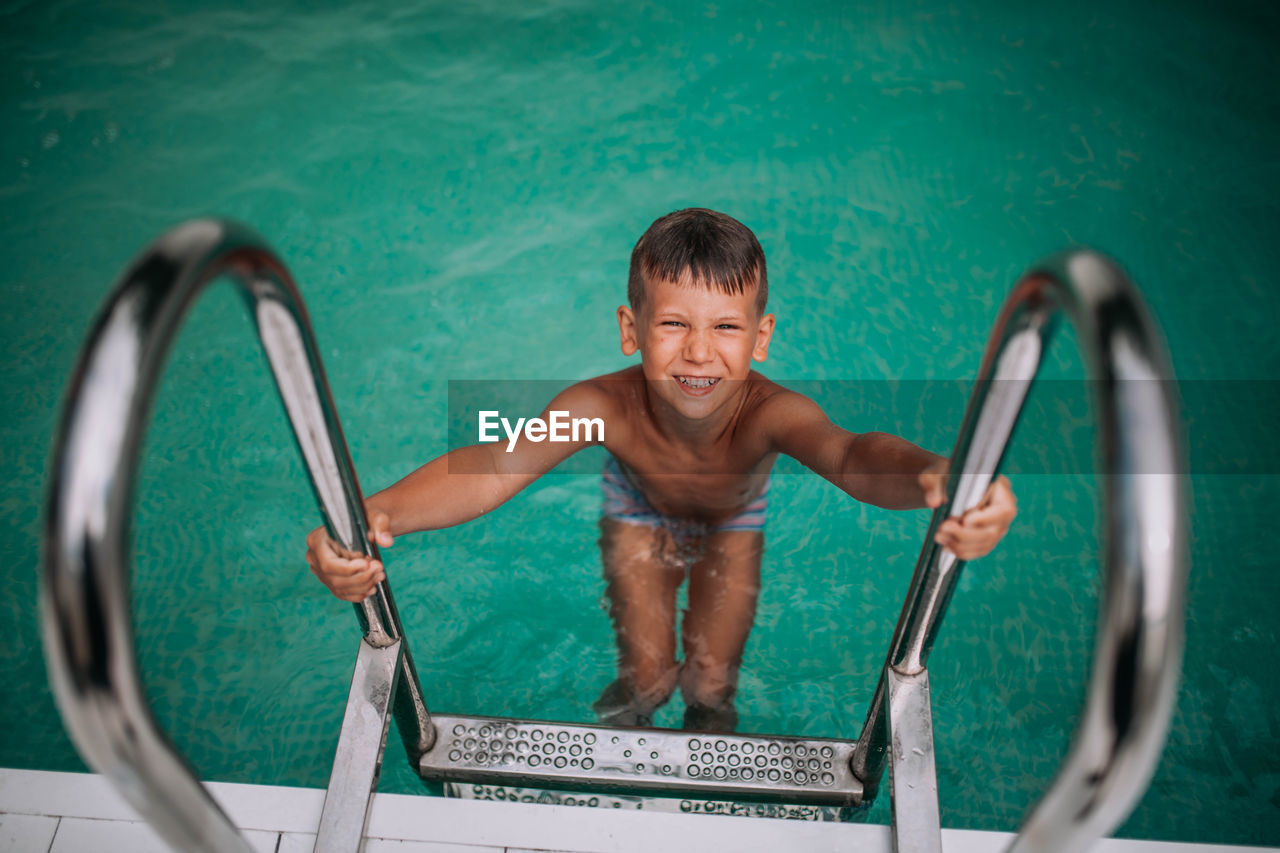 High angle view of smiling boy in swimming pool