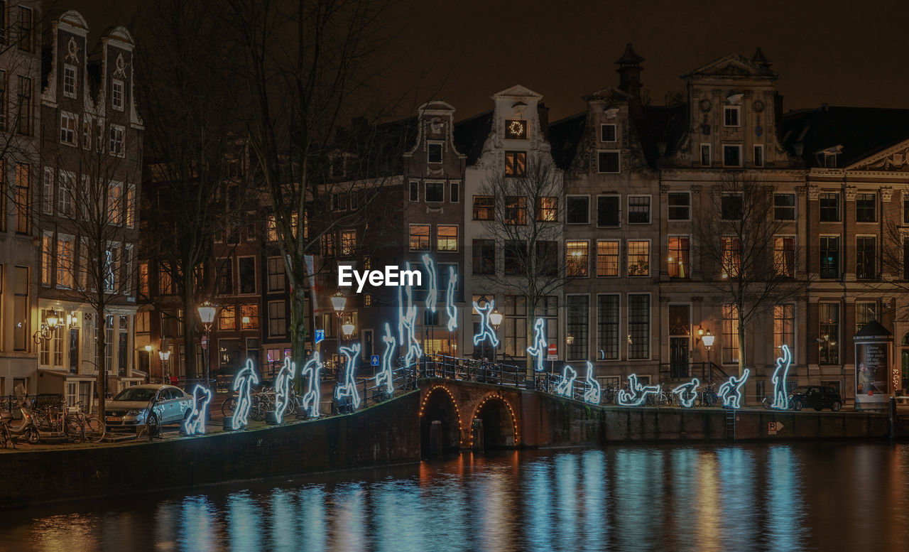 Illuminated decorations on bridge over river in residential district