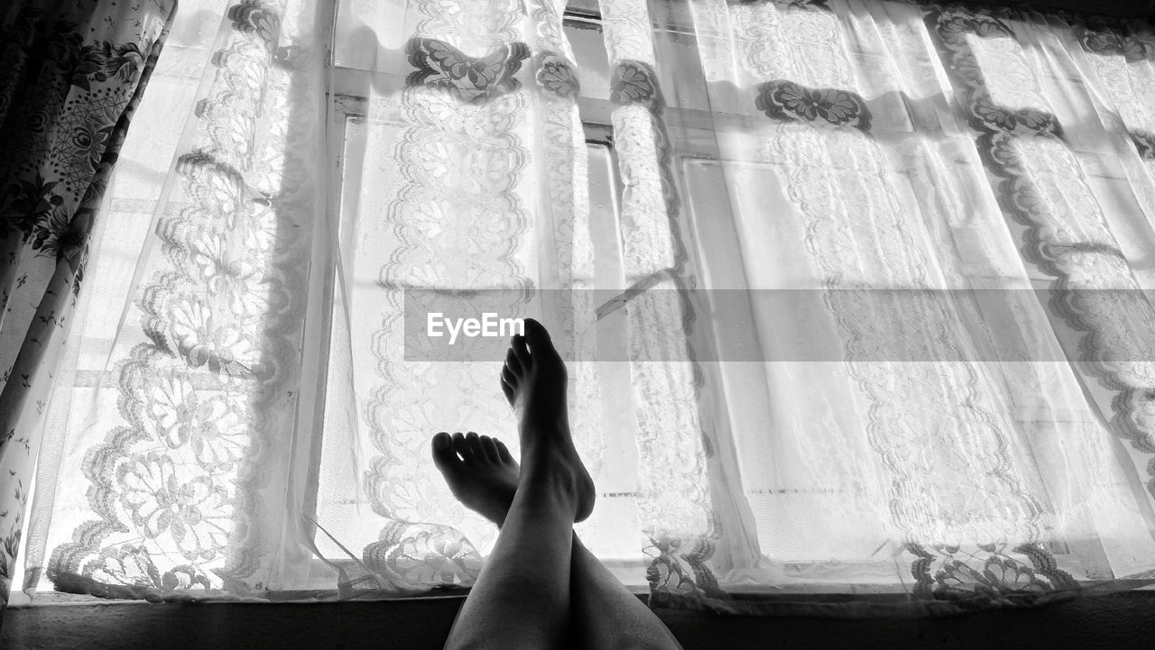 Low section of woman on window sill