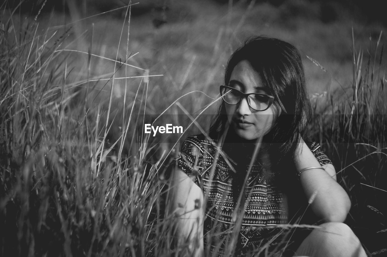 Young woman sitting amidst grass on field