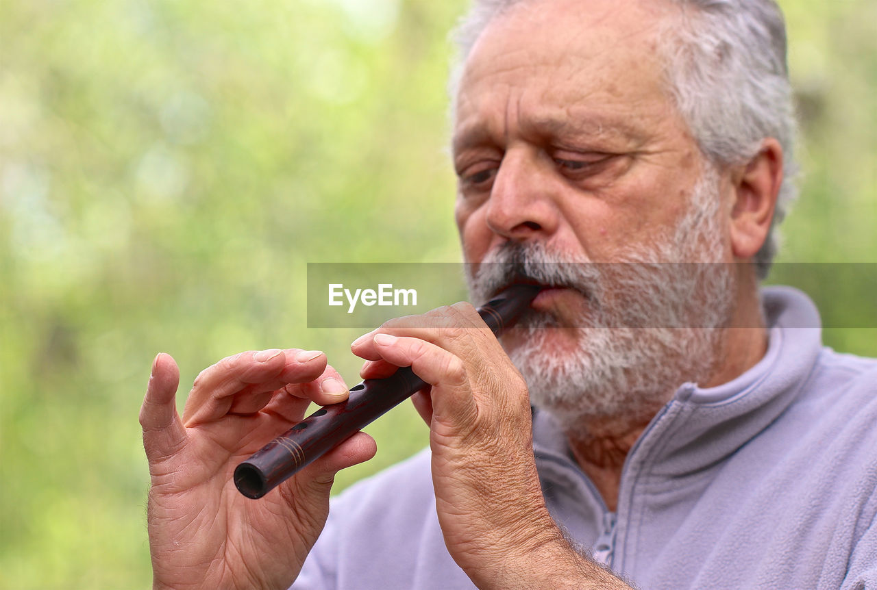 Man playing flute while standing outdoors