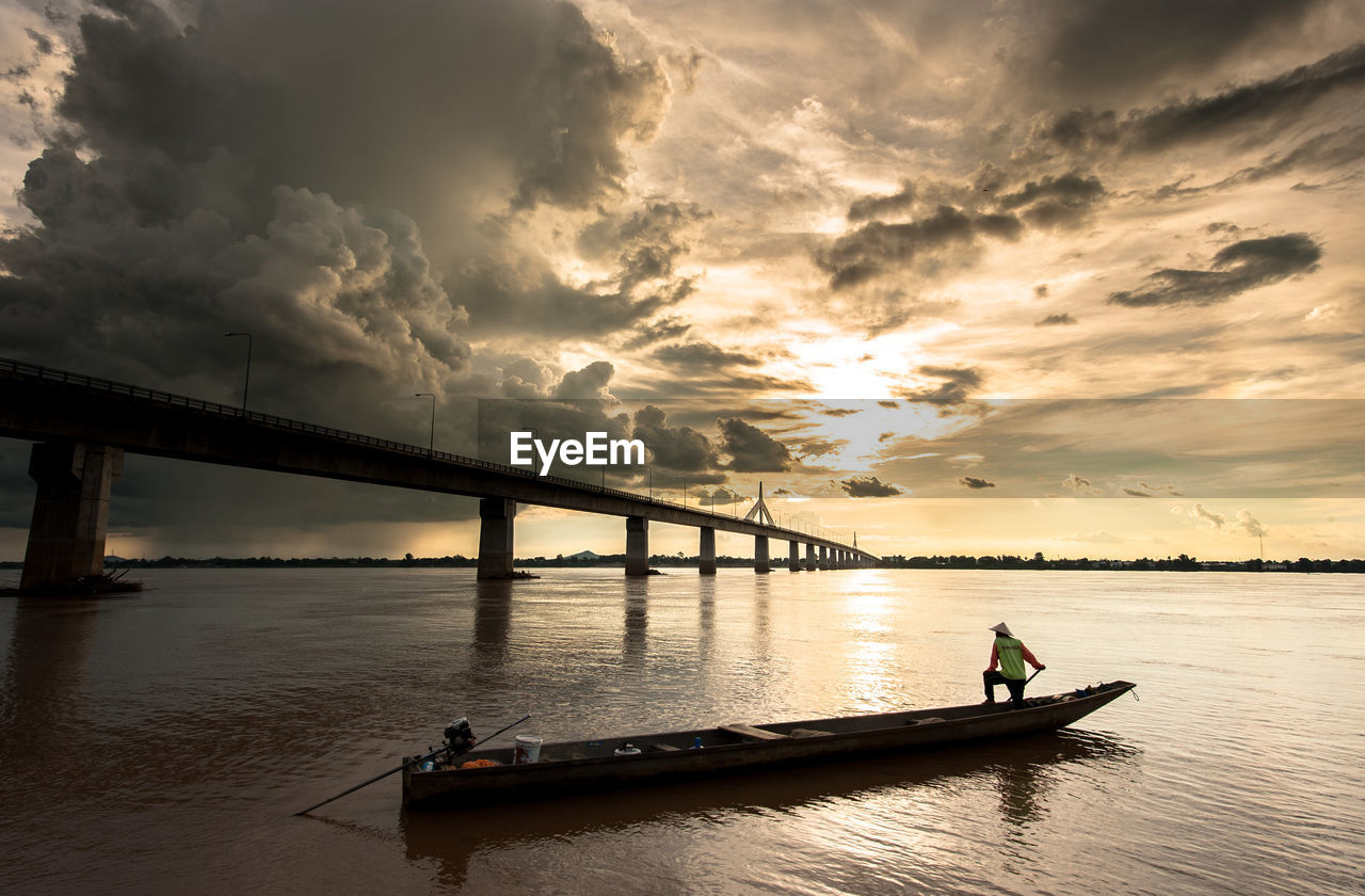 Silhouette bridge over river against sky during sunset