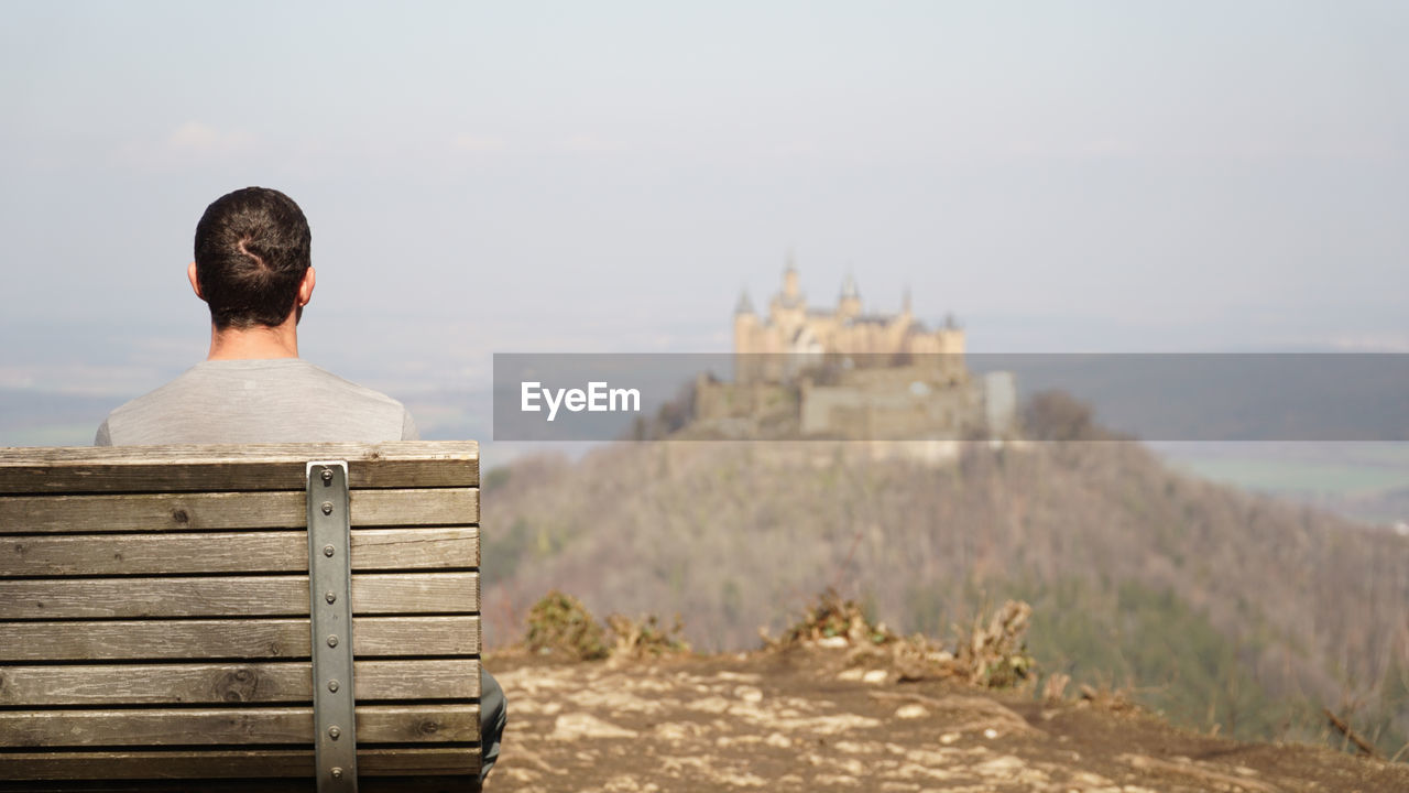 Person looking at hohenzollern castle sitting on top of a hilltop in baden-württemberg, germany.