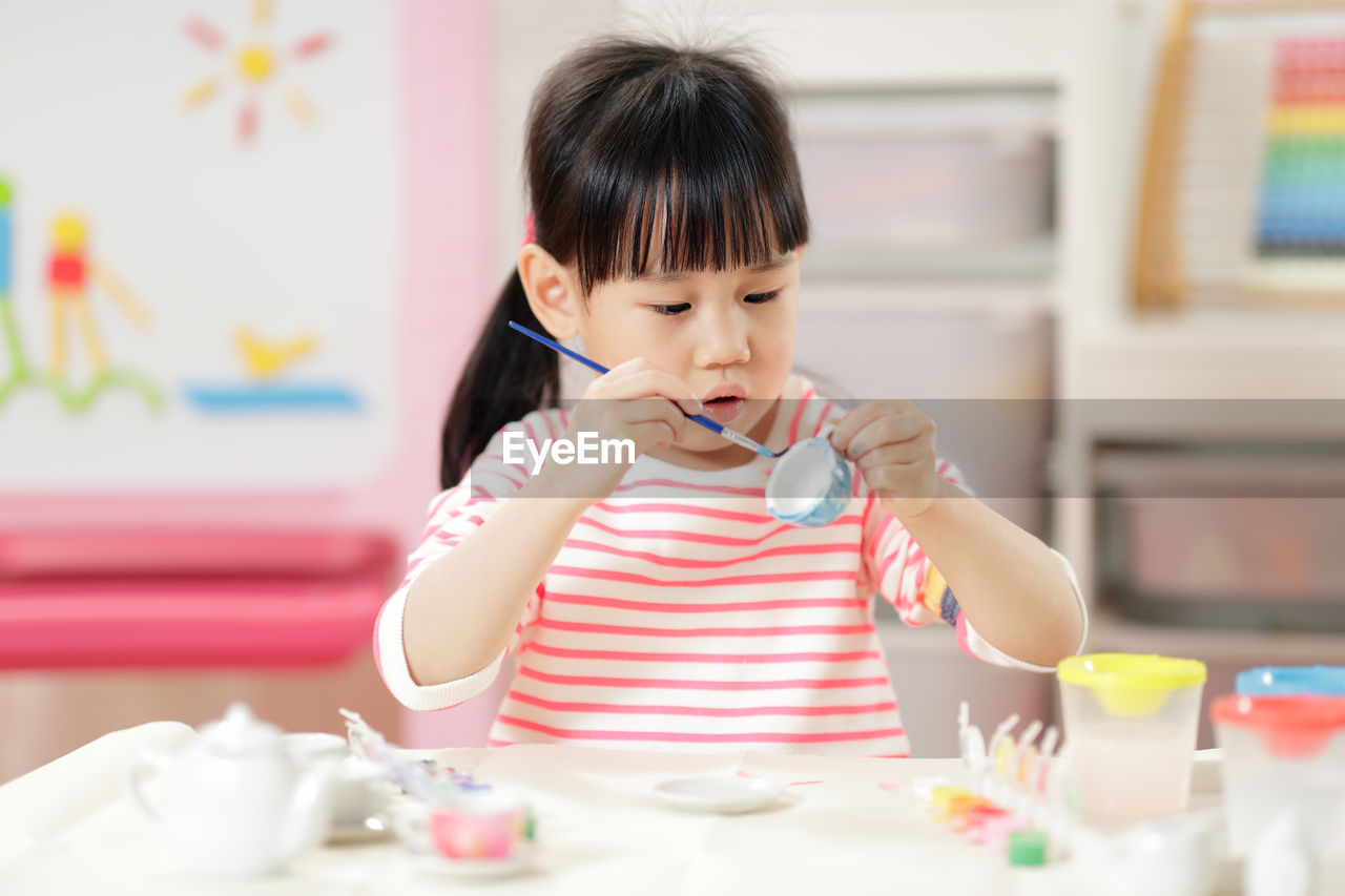 Young girl decorating hand made craft for homeschooling