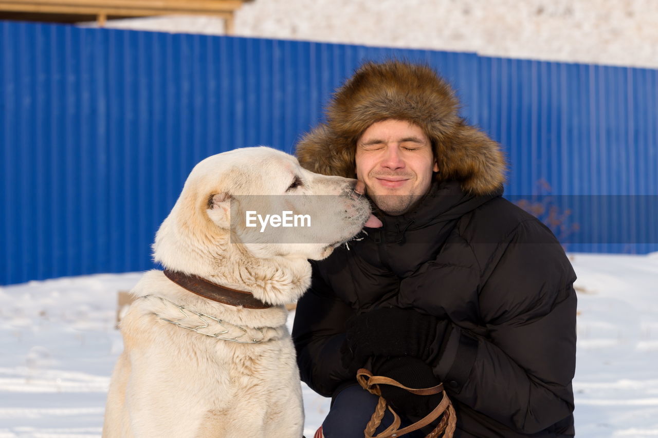 The dog licks the face of the guy on the street.